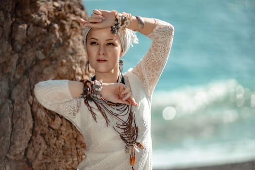 Middle aged woman looks good with blond hair, boho style in white long dress on the beach decorations on her neck and arms