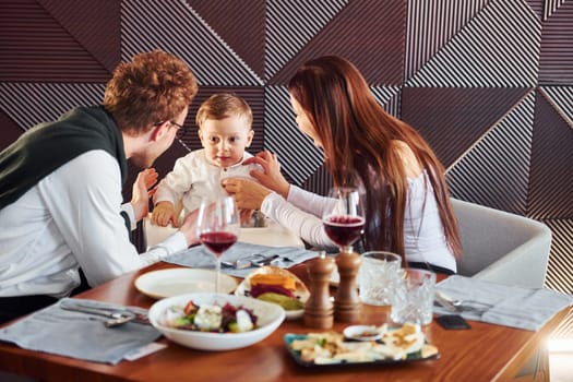 Young guy, woman and little boy. Indoors of new modern luxury restaurant.
