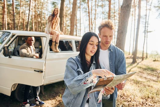 Group of young people is traveling together in the forest at daytime.