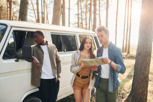 Group of young people is traveling together in the forest at daytime.