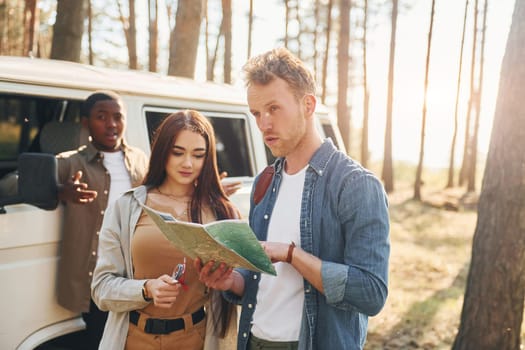 Group of young people is traveling together in the forest at daytime.