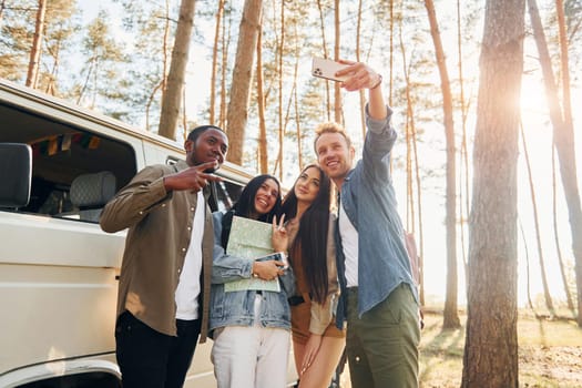 Making selfie. Group of young people is traveling together in the forest at daytime.