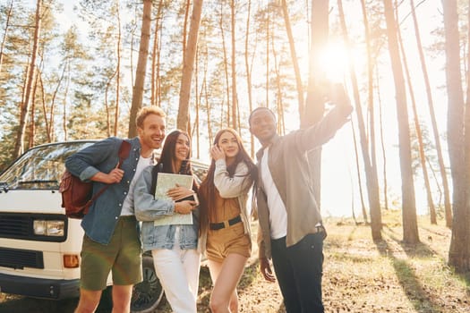 Making selfie. Group of young people is traveling together in the forest at daytime.