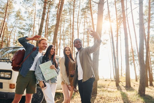 Making selfie. Group of young people is traveling together in the forest at daytime.