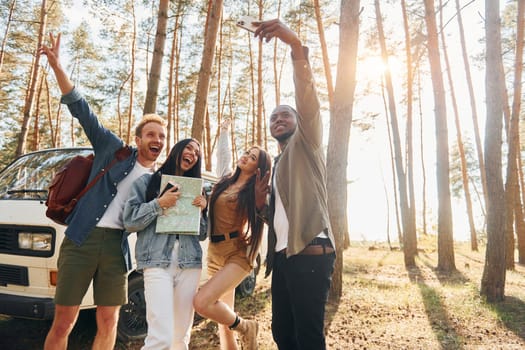 Making selfie. Group of young people is traveling together in the forest at daytime.