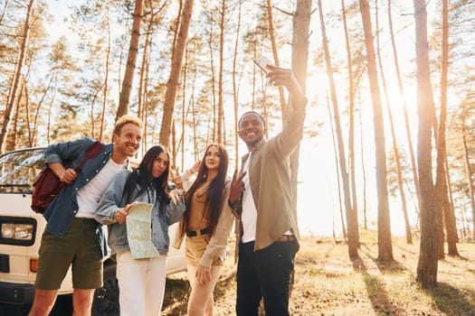 Making selfie. Group of young people is traveling together in the forest at daytime.