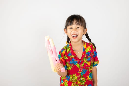 Happy Songkran Day, Asian kid girl with floral shirt hold water gun, Thai child funny hold toy water pistol and smile, isolated on white background, Thailand Songkran festival national culture concept