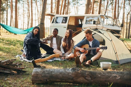 Camp and car. Group of young people is traveling together in the forest at daytime.