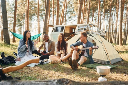 Sitting and resting. Group of young people is traveling together in the forest at daytime.