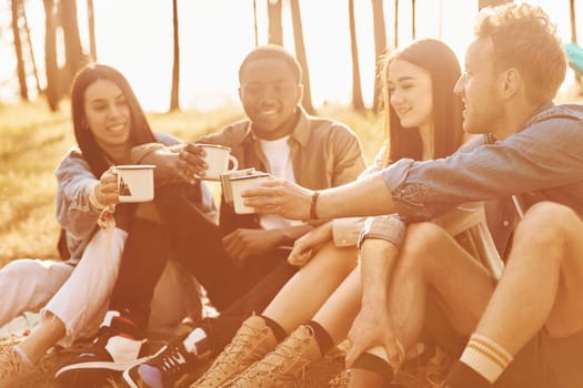 Sitting and resting. Group of young people is traveling together in the forest at daytime.