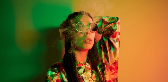 Smoking, activity. Fashionable young woman standing in the studio with neon light.