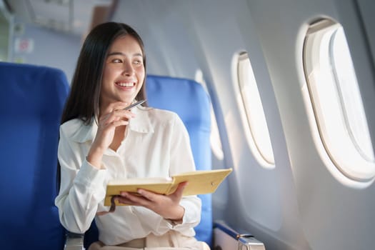 Asian business woman passenger sitting on business class luxury plane while working using notebook book while travel concept.