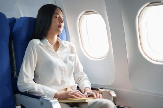 Asian attractive business woman passenger sitting on business class luxury plane while relax while travel concept.