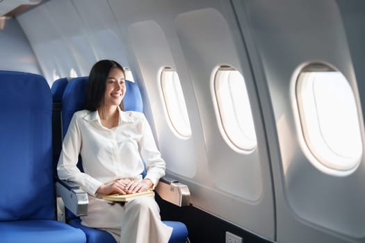 Asian attractive business woman passenger sitting on business class luxury plane while relax while travel concept.