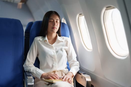 Asian attractive business woman passenger sitting on business class luxury plane while relax while travel concept.