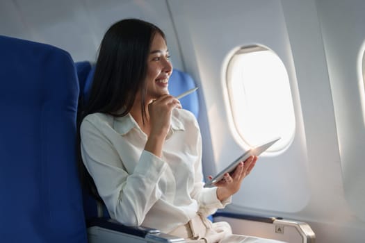 Asian attractive business woman passenger sitting on business class luxury plane while tablet computer while travel concept.