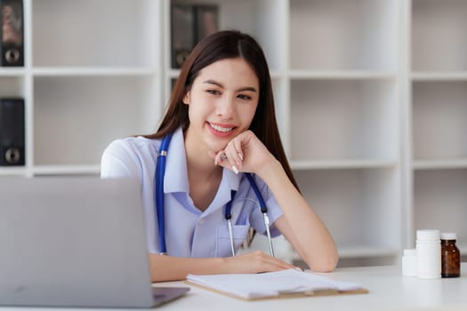 Smiling Happy and Beautiful Doctor working on laptop at clinic, health care, medical, healthy concept.