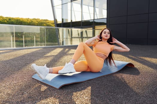 Modern exterior. Young woman in sportswear have fitness session outdoors.