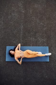 Top view. Leaning on the mat. Young woman in sportswear have fitness session outdoors.