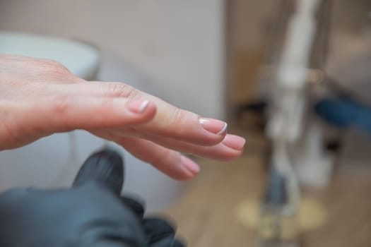 A master manicurist makes a drawing french manicure nails using white varnish and a thin brush, Manicure process, High quality photo