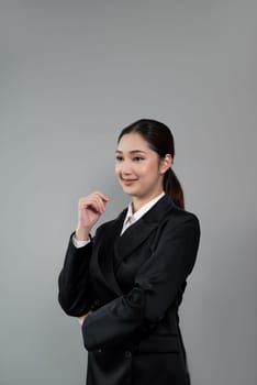 Confident young businesswoman stands on isolated background, posing in formal black suit. Office lady or manager with smart and professional appearance. Enthusiastic