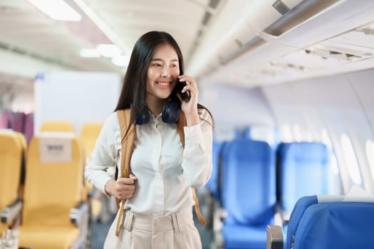 Asian business woman passenger sitting on business class luxury plane while working using smart phone mobile talking or video conference and travel concept.