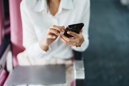 Asian business woman passenger sitting on business class luxury plane while working using smart phone mobile talking or video conference and travel concept.