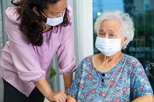 Caregiver help Asian senior woman on wheelchair and wearing a face mask for protect safety infection Covid19 Coronavirus.