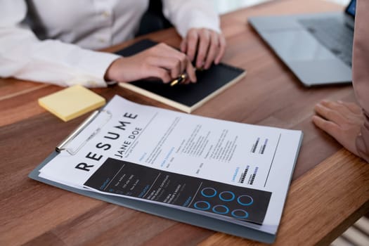 Closeup resume paper with qualifications on the desk during job interview in the office with young applicant candidates and interviewer, discussing on application of the position. Enthusiastic