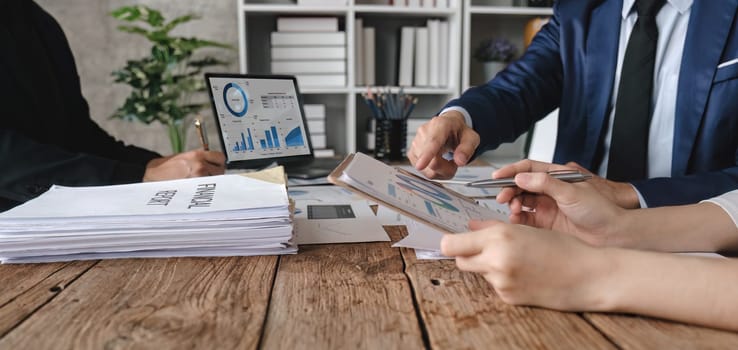 Business People Meeting using laptop computer,calculator,notebook,stock market chart paper for analysis Plans to improve quality next month. Conference Discussion Corporate Concept....