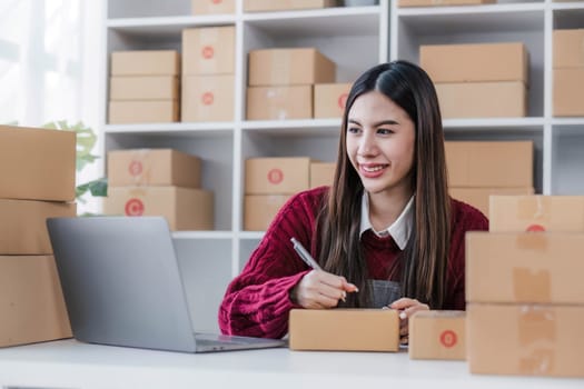 Startup small business entrepreneur SME, asian woman packing cloth in box. Portrait young Asian small business owner home office, online sell marketing delivery, SME e-commerce telemarketing concept...