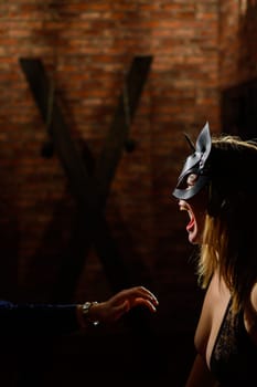 BDSM A woman in a leather cat mask obeys her lover. Role-playing games for adults. The man dominates and punishes the mistress. Sensual lips. Married couple