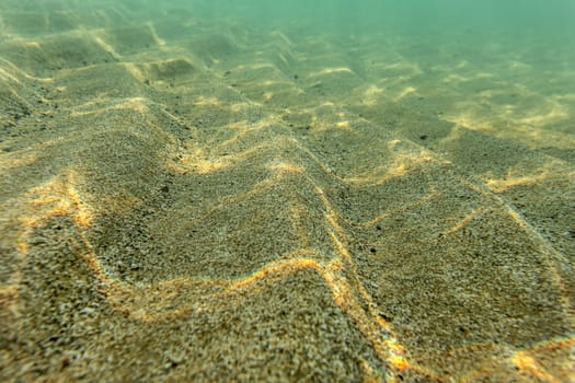 Shallow sea bottom, sand "dunes" lit by sun. Abstract marine background.