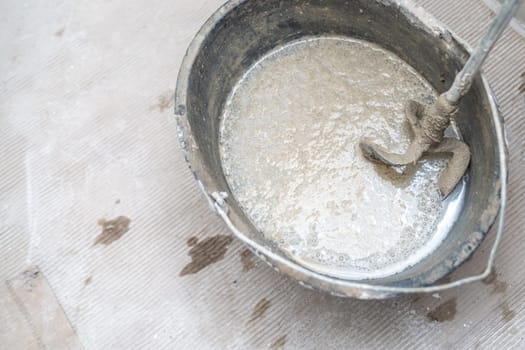 manual mixing of cement with the help of an electric mixer, cement in a bucket on a construction site. High quality photo