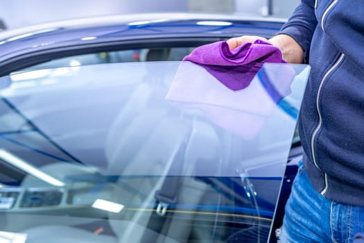 manual cleaning of car windows with a microfiber towel in the garage. High quality photo
