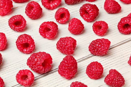 Raspberries spilled on white boards desk.