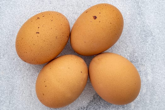 Top down view of four brown speckled eggs on a marble countertop. High quality photo
