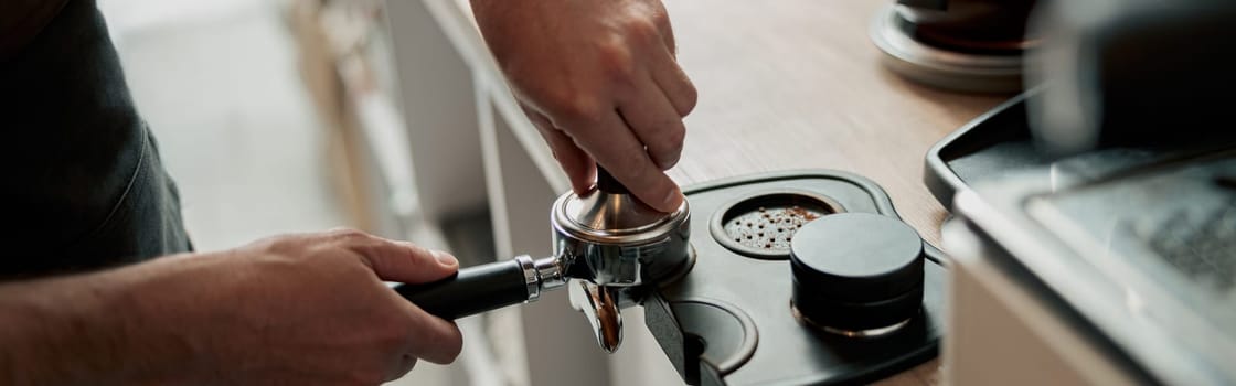 Male person holding portafilter and preparing coffee in bar. Coffeehouse and cafeteria