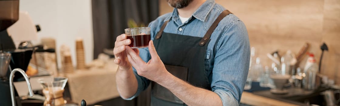 Close up of barista holds a glass of fragrant filter coffee in his hands