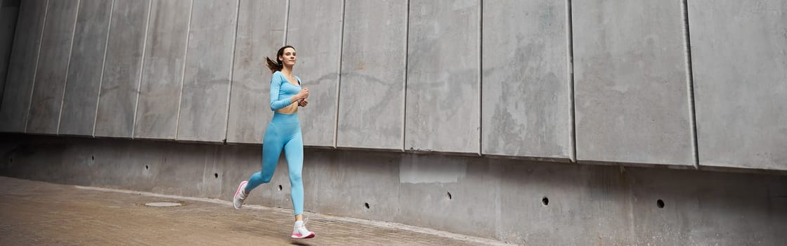 Beautiful fit young woman jogger is running outdoors