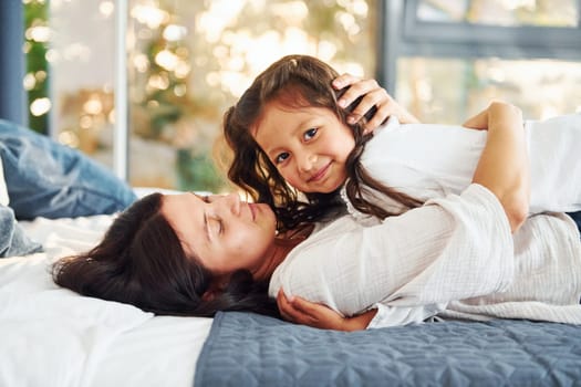 Lying down on the bed. Mother and her daughter spending time together at home.