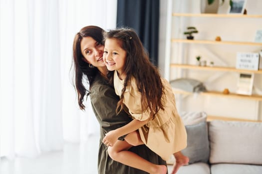 Girl is on the hands of woman. Mother and her daughter spending time together at home.