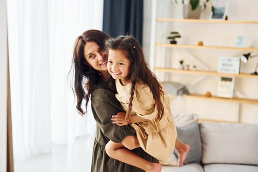 Girl is on the hands of woman. Mother and her daughter spending time together at home.