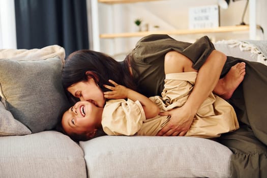 Lying down on the bed. Mother and her daughter spending time together at home.