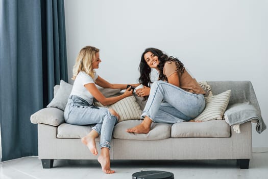 Sitting on bed. Two women is together at home.