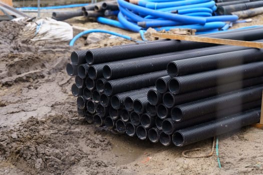 Blue and black corrugated pipelines of various diameters lie on a construction site on the street. Repair of communications.