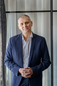 Portrait of a mature calm businessman with his jacket unbuttoned. Vertical frame.