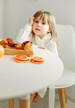 Portrait of a young girl in a dressing gown, who is sitting in the kitchen, next to a box of marmalade, candied fruits.