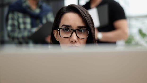 Confident business woman in casual clothes sitting in the office and working on a laptop