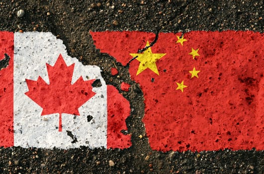 On the pavement, there are images of the flags of Canada and China, as a symbol of the confrontation between the countries. Conceptual image.